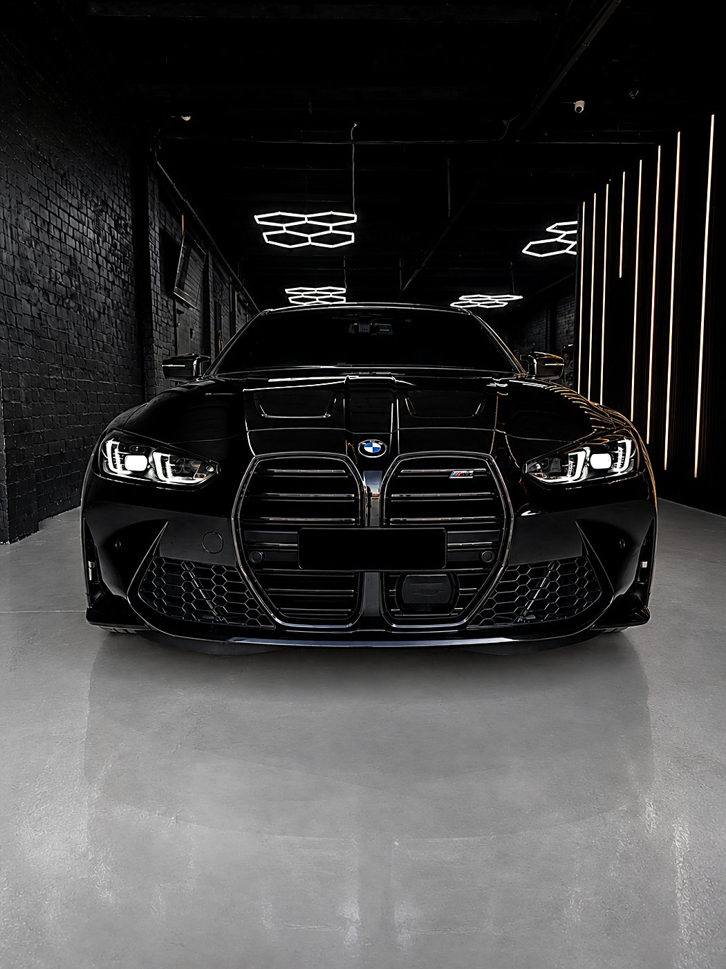 Finished black BMW M4 front-on under studio lights