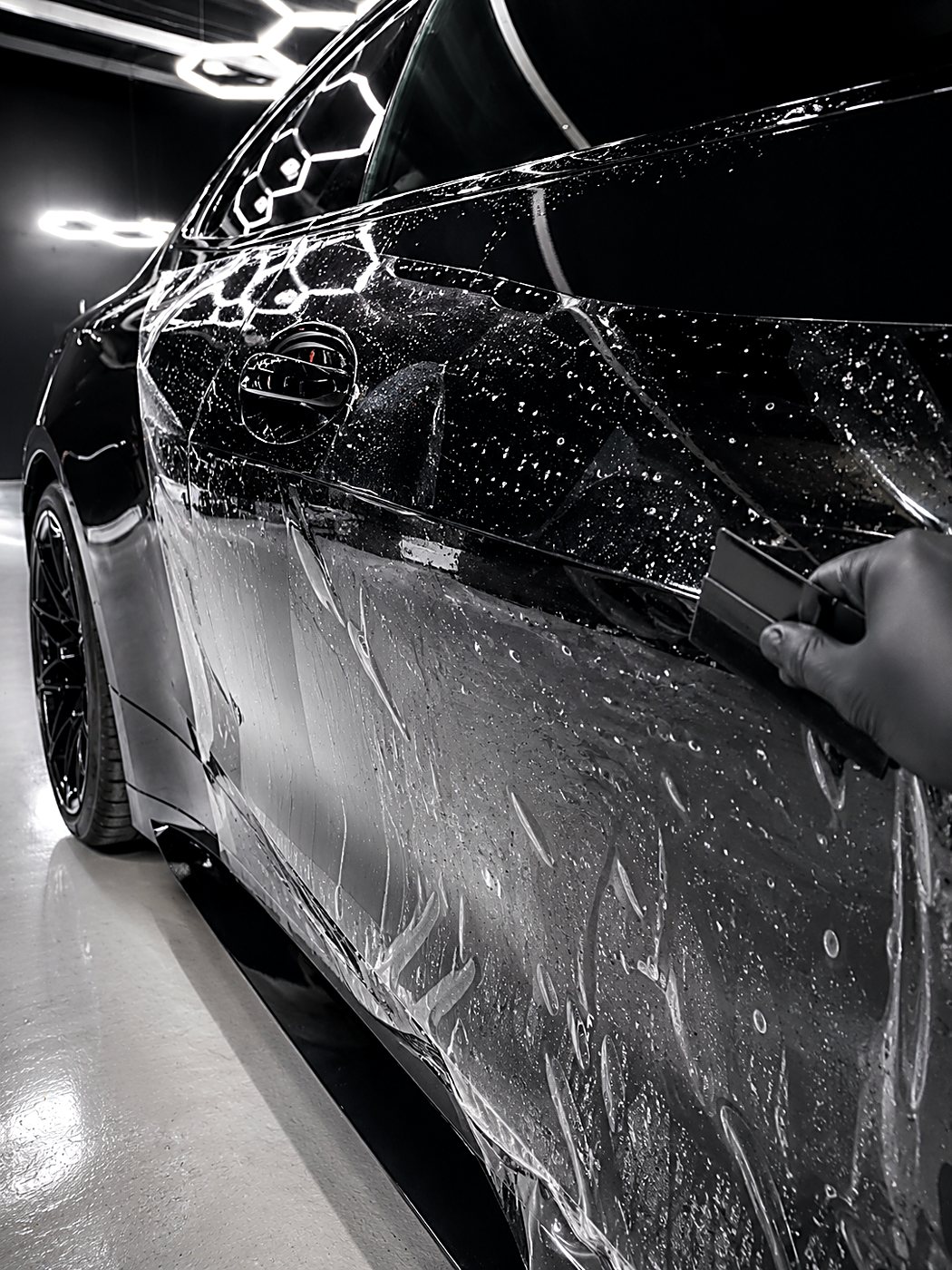 Paint protection film being squeegeed onto a black BMW